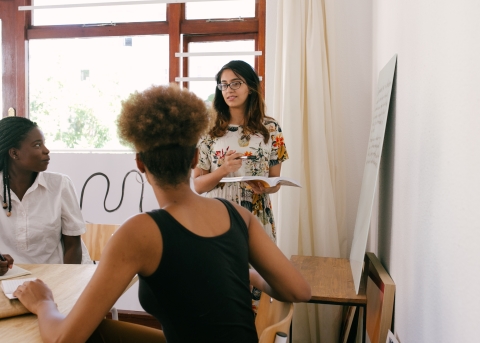 Woman standing and talking to seated coworkers